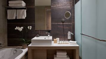 Un baño moderno con una bañera grande, un tocador de madera con un lavabo y un espejo.