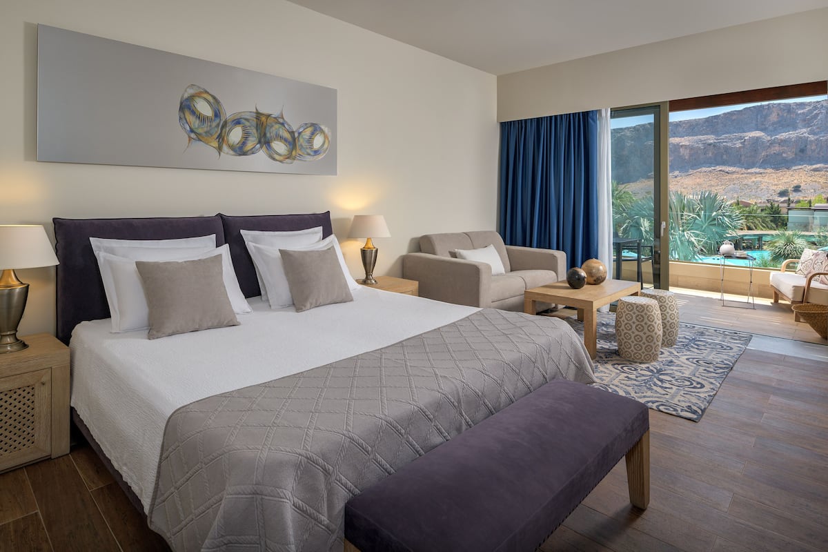 Une chambre d’hôtel avec un grand lit, un canapé, un bureau et une vue sur un paysage montagneux.
