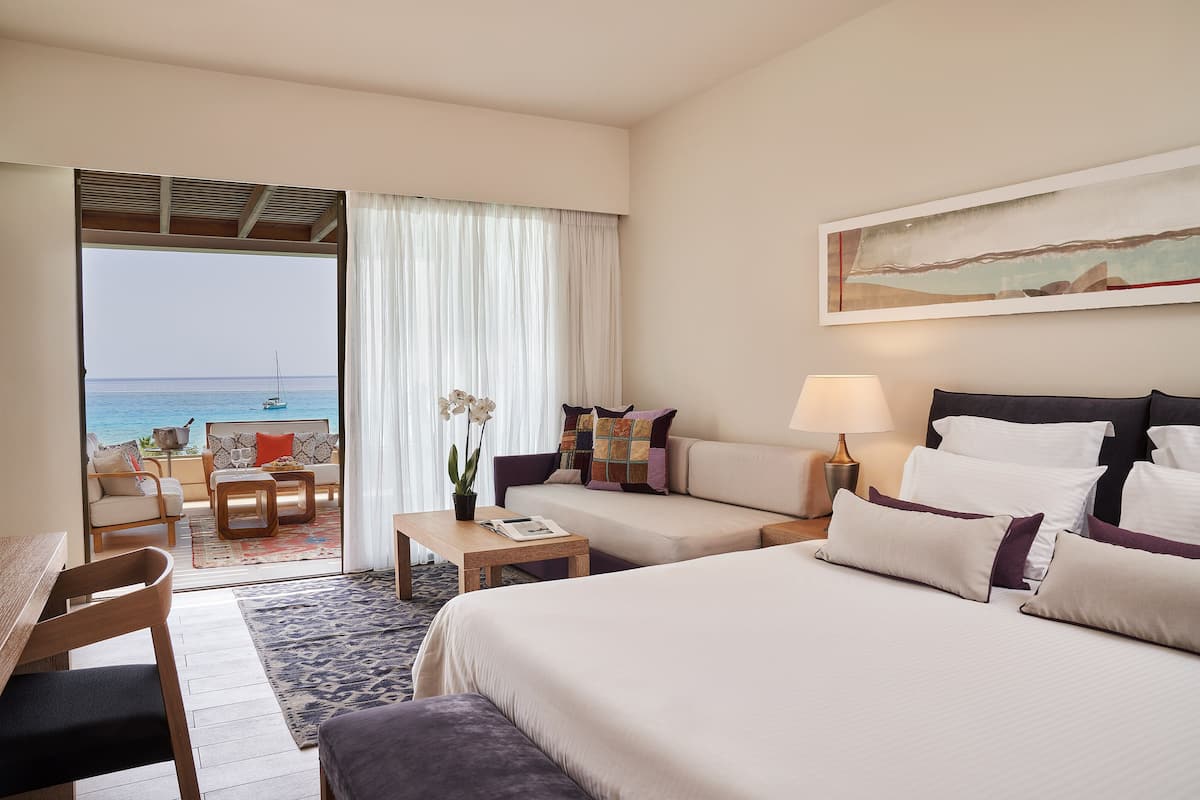 Une chambre d’hôtel avec un lit, un canapé, un bureau et une vue sur la mer.