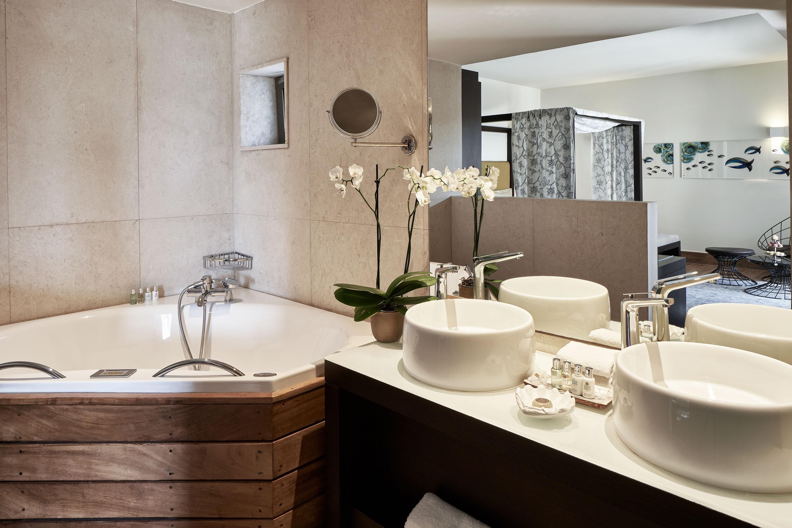 Un baño moderno con una bañera grande, dos lavamanos redondos y un espejo.