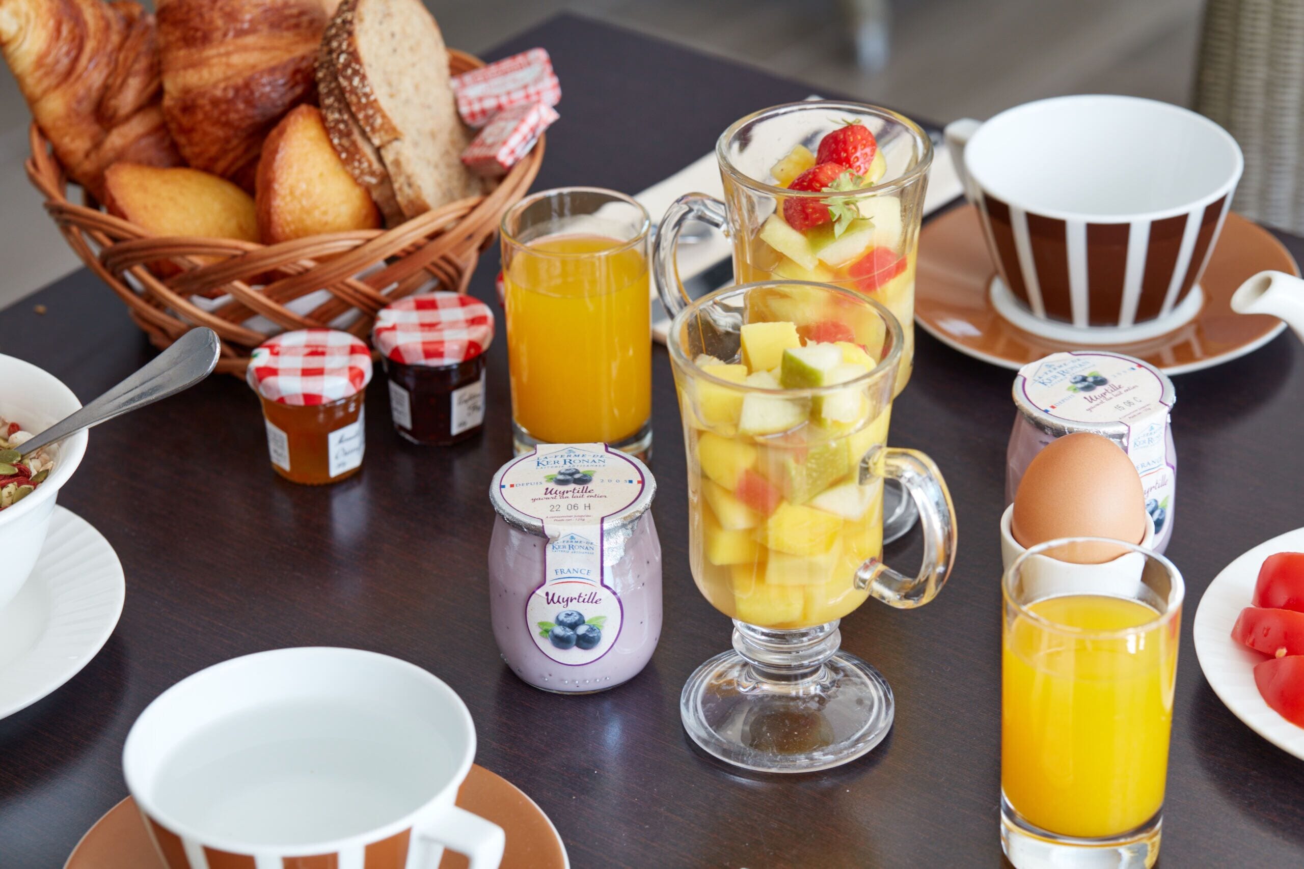 A breakfast table with various food items, including bread, fruit, and beverages.