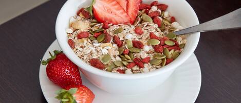 A bowl of cereal with strawberries and seeds on a white plate.