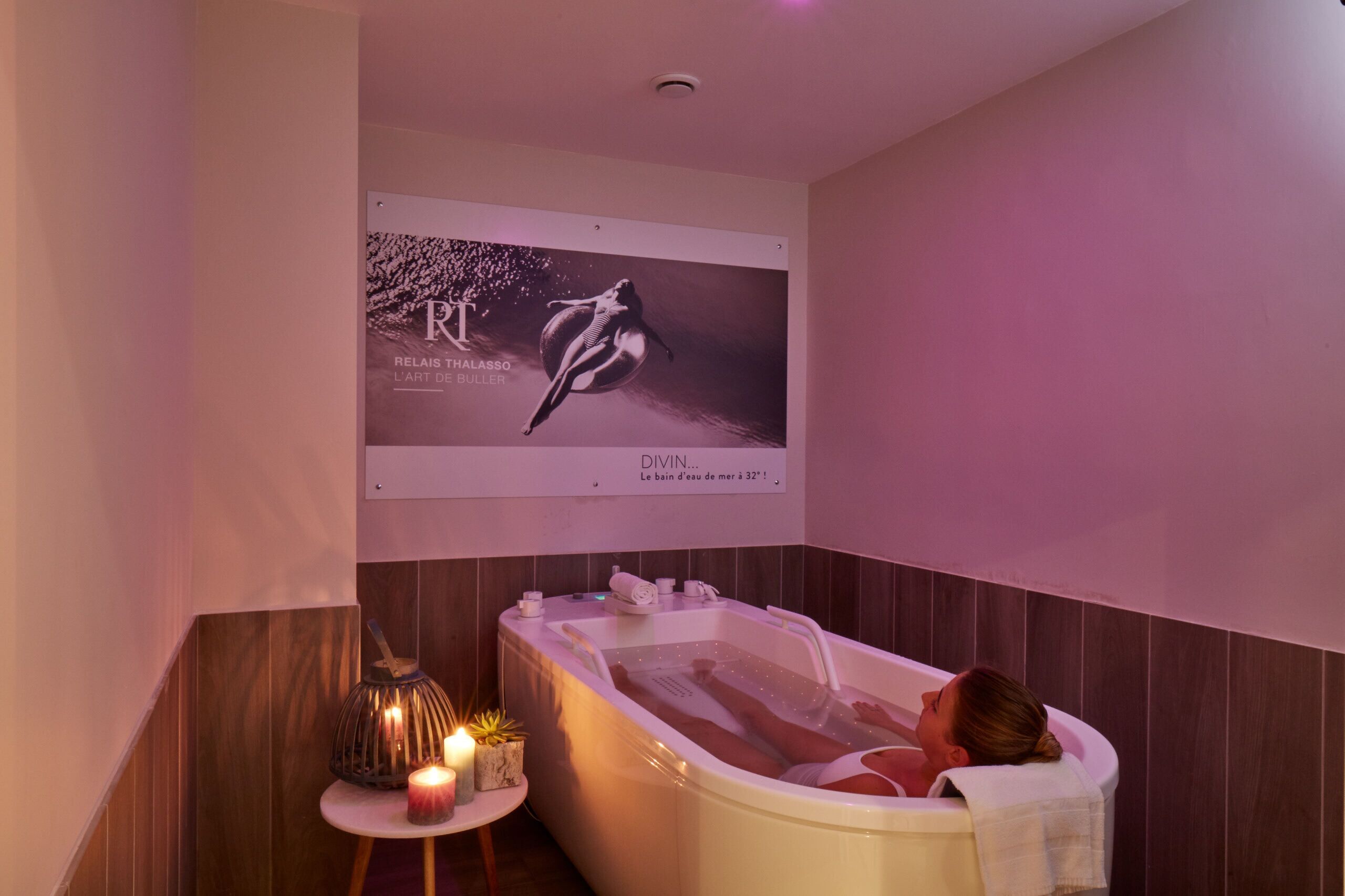 A woman relaxing in a bathtub with a poster on the wall behind her.
