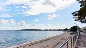 A beach with a wooden boardwalk, a sandy shore, and a calm sea. - Kastel Wellness Hôtel Thalasso & Spa (Benodet)