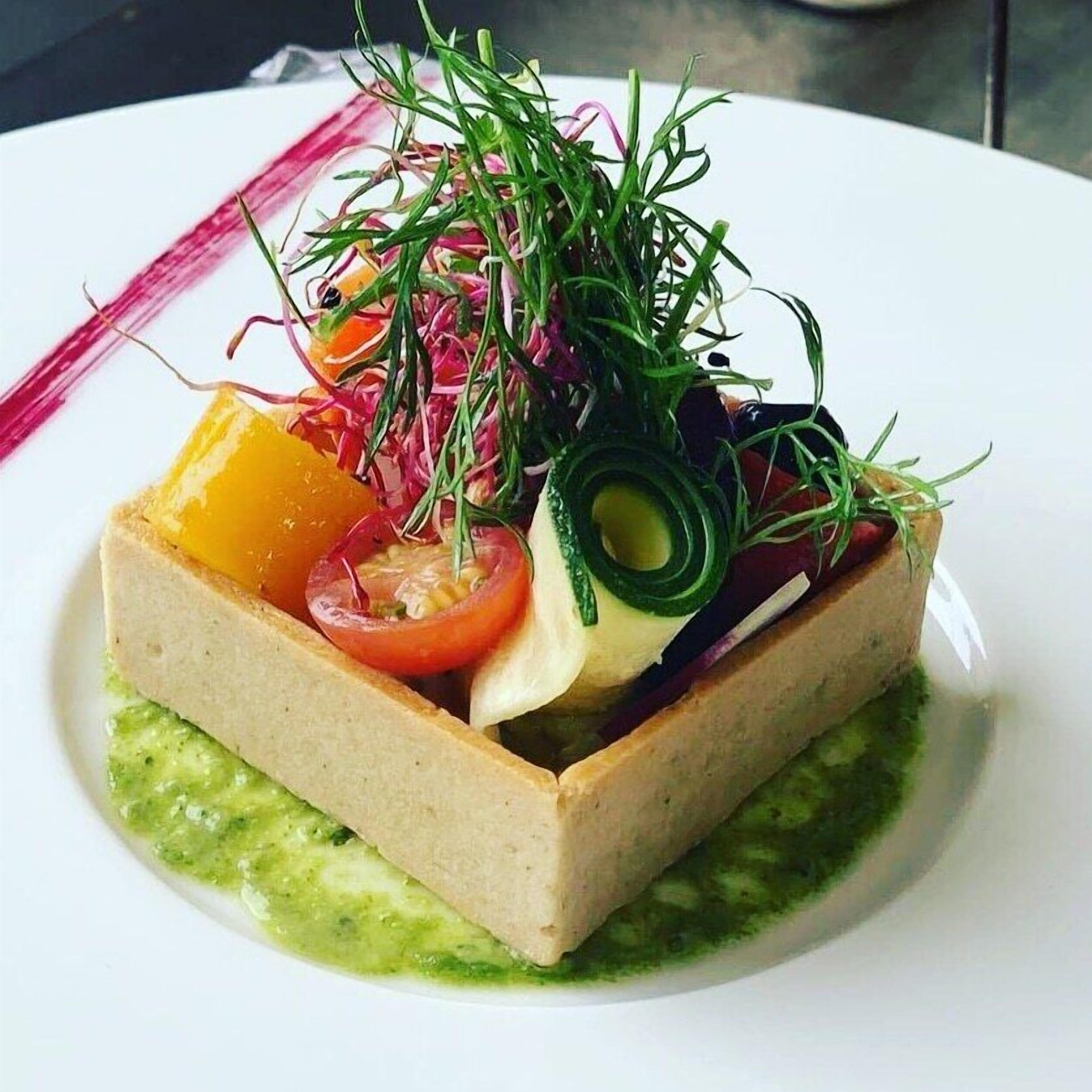 Un plato rectangular con diversos vegetales y salsa.