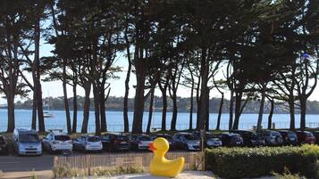 Un estacionamiento con coches y una gran escultura de pato amarillo.