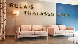 A reception area with two sofas, a lamp, and a wall with 'RELAIS THALASSO & SPA' signage. - Kastel Wellness Hôtel Thalasso & Spa (Benodet)