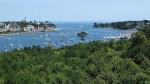 A coastal town with a marina filled with boats, surrounded by dense greenery and buildings along the shore. - Kastel Wellness Hôtel Thalasso & Spa (Benodet)