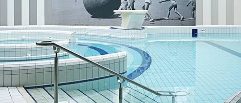 A swimming pool with tiled flooring and a central hot tub area.