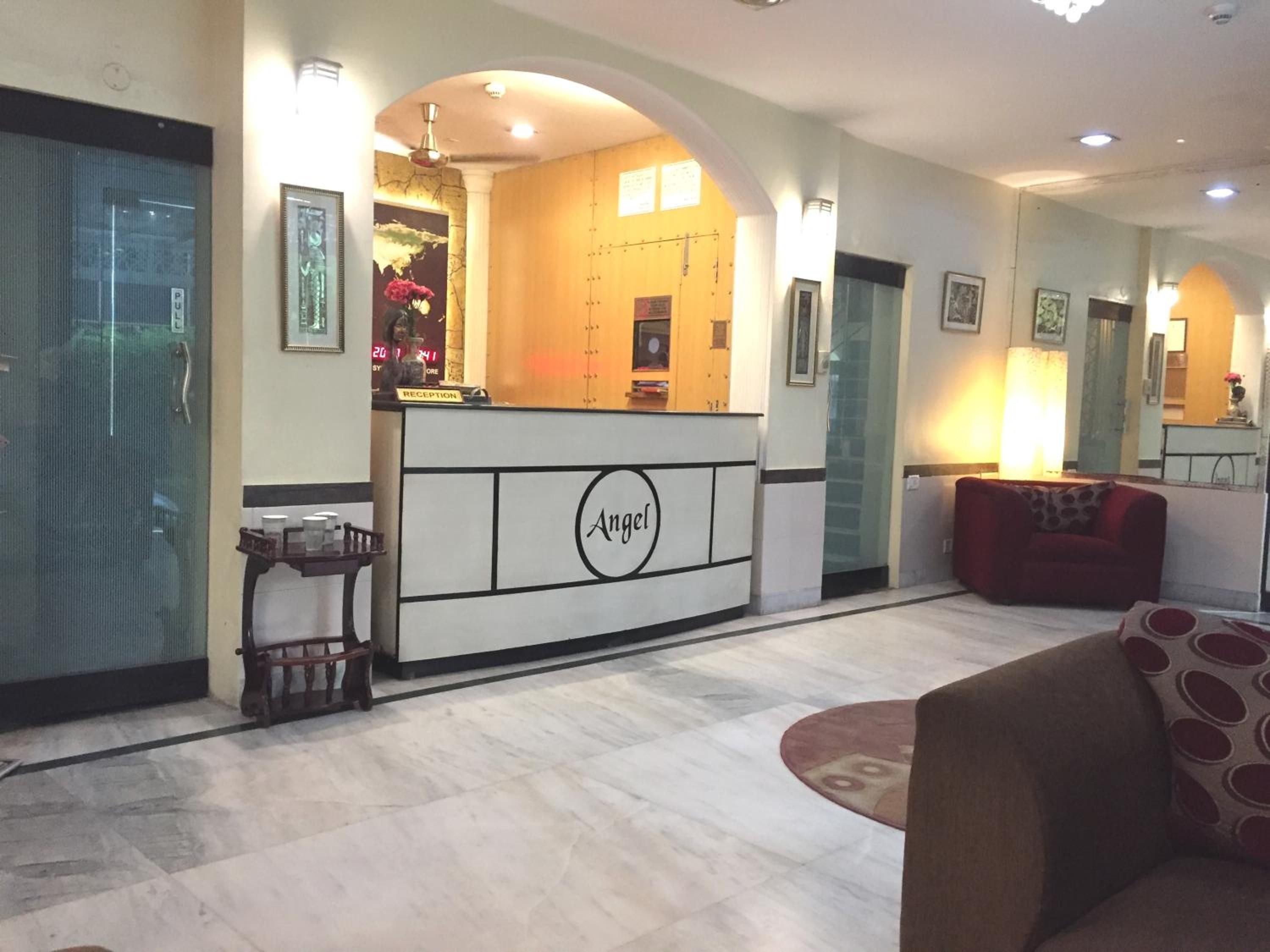 A reception desk with a sign reading 'Angel' in a hotel lobby with a red sofa and a patterned rug.