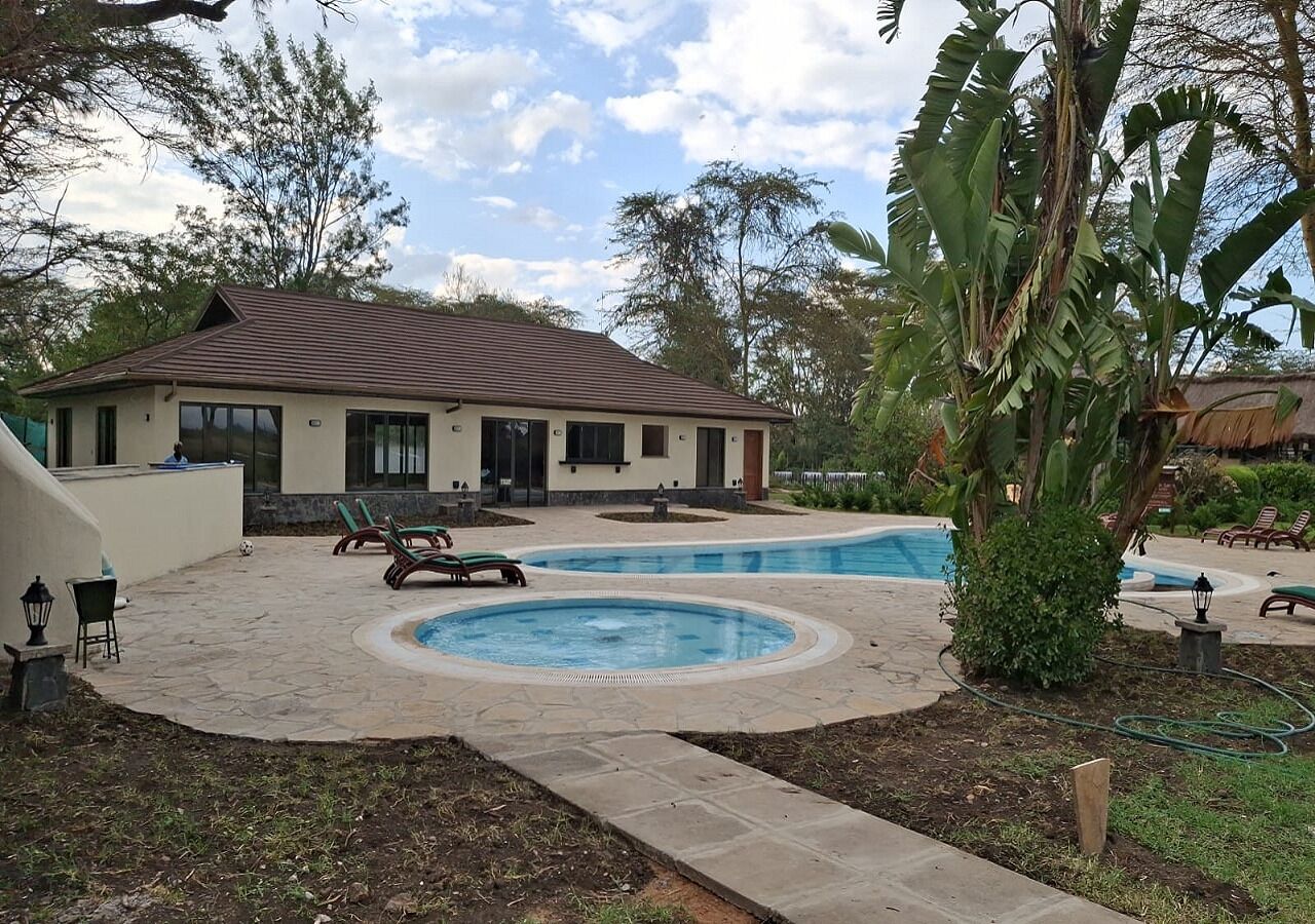 Una casa con piscina, mobiliario de exterior y jardín.