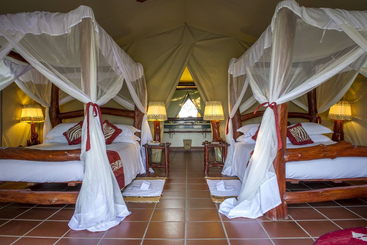 A room with four beds, each with a canopy and bedside lamps.