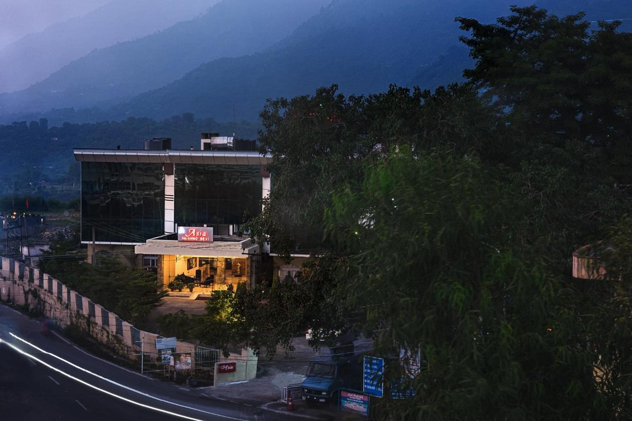 A modern building with a glass facade, a signboard, and a well-lit entrance.