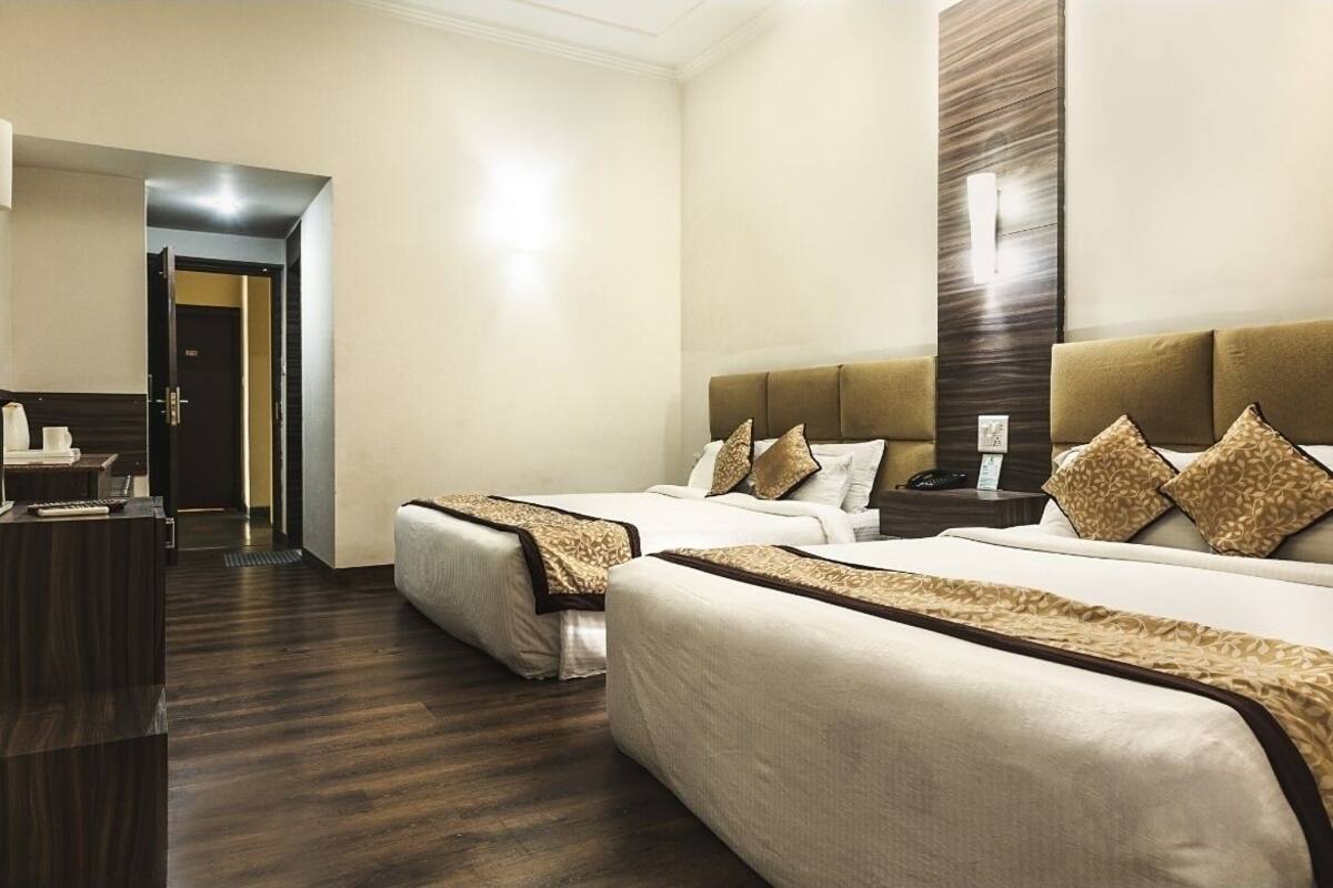 A hotel room with two beds, a desk, and a mirror.