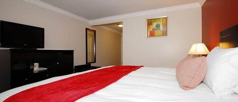 A hotel room with a bed, a TV, a desk, and a lamp.