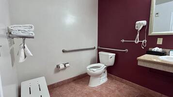 Ein Badezimmer mit Toilette, Handtrockner, Handtuchhalter und Waschbecken mit Spiegel darüber.