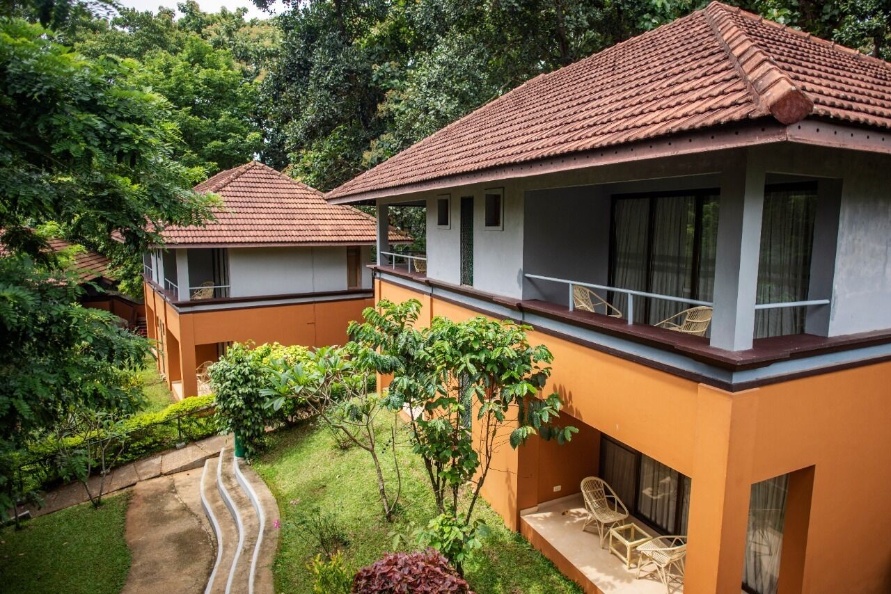 A bungalow with a tiled roof, a balcony with wicker furniture, and a garden with a curved pathway.