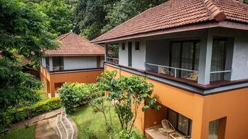 A bungalow with a tiled roof, a balcony with wicker furniture, and a garden with a curved pathway.