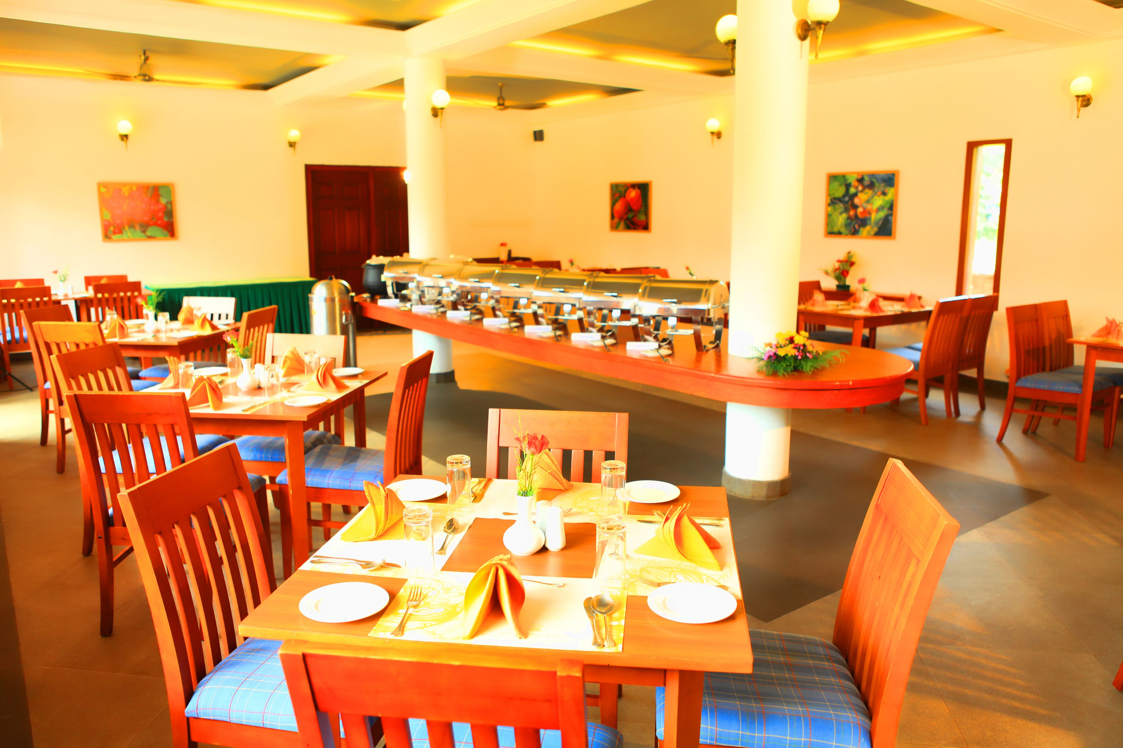 Un restaurante con varias mesas y sillas, una zona de bufé y obras de arte en las paredes.