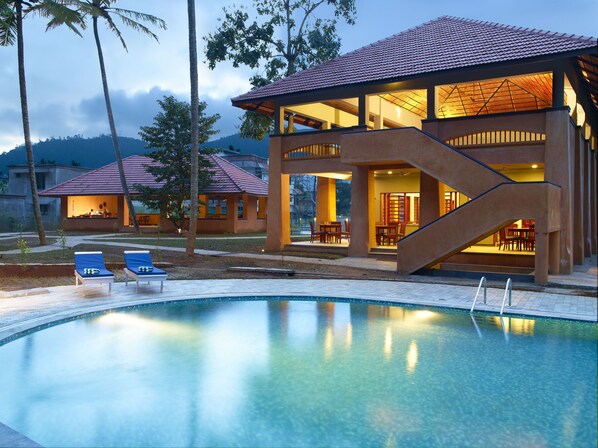 Una piscina al aire libre, sillones reclinables de piscina