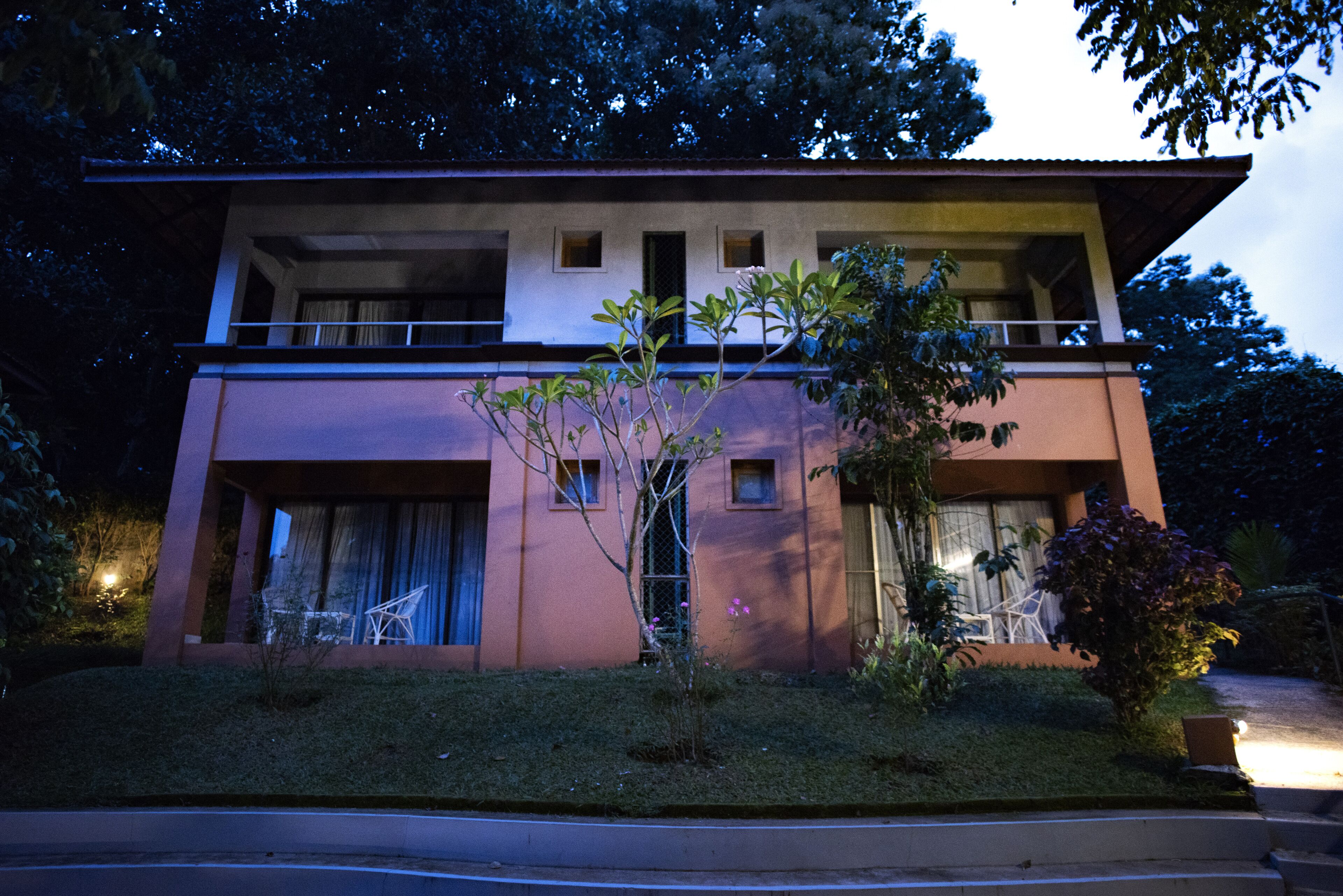 A two-story building with a balcony, large windows, and a well-maintained garden.