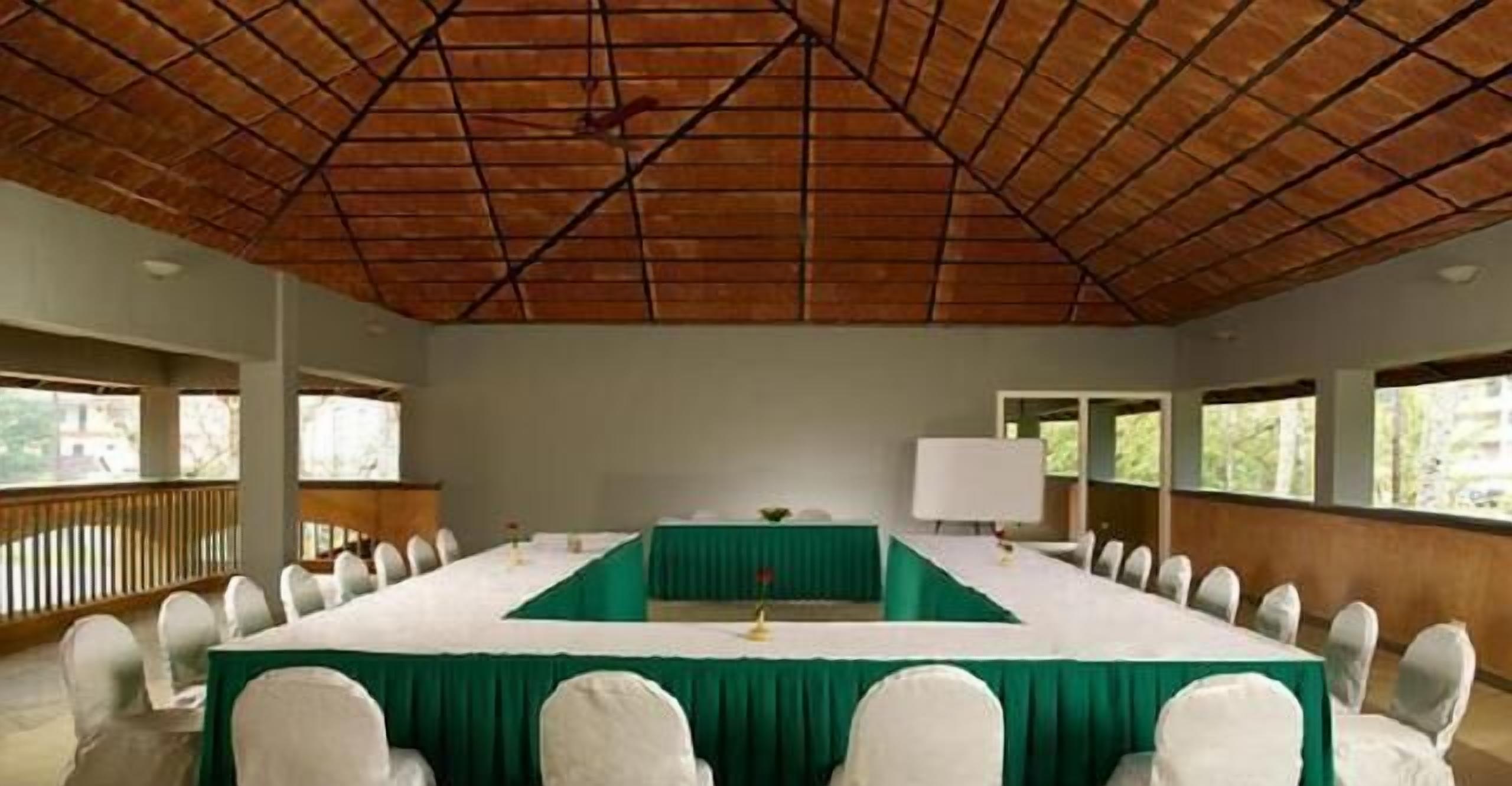 A conference room with a long table, white chairs, and a green tablecloth.