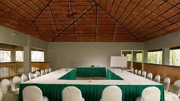 A conference room with a long table, white chairs, and a green tablecloth.
