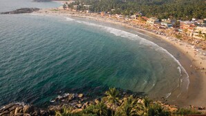 A coastal town with a beach, buildings, and a forested hill. - Abad Harmonia Ayurveda Beach Resort (Neyyattinkara)