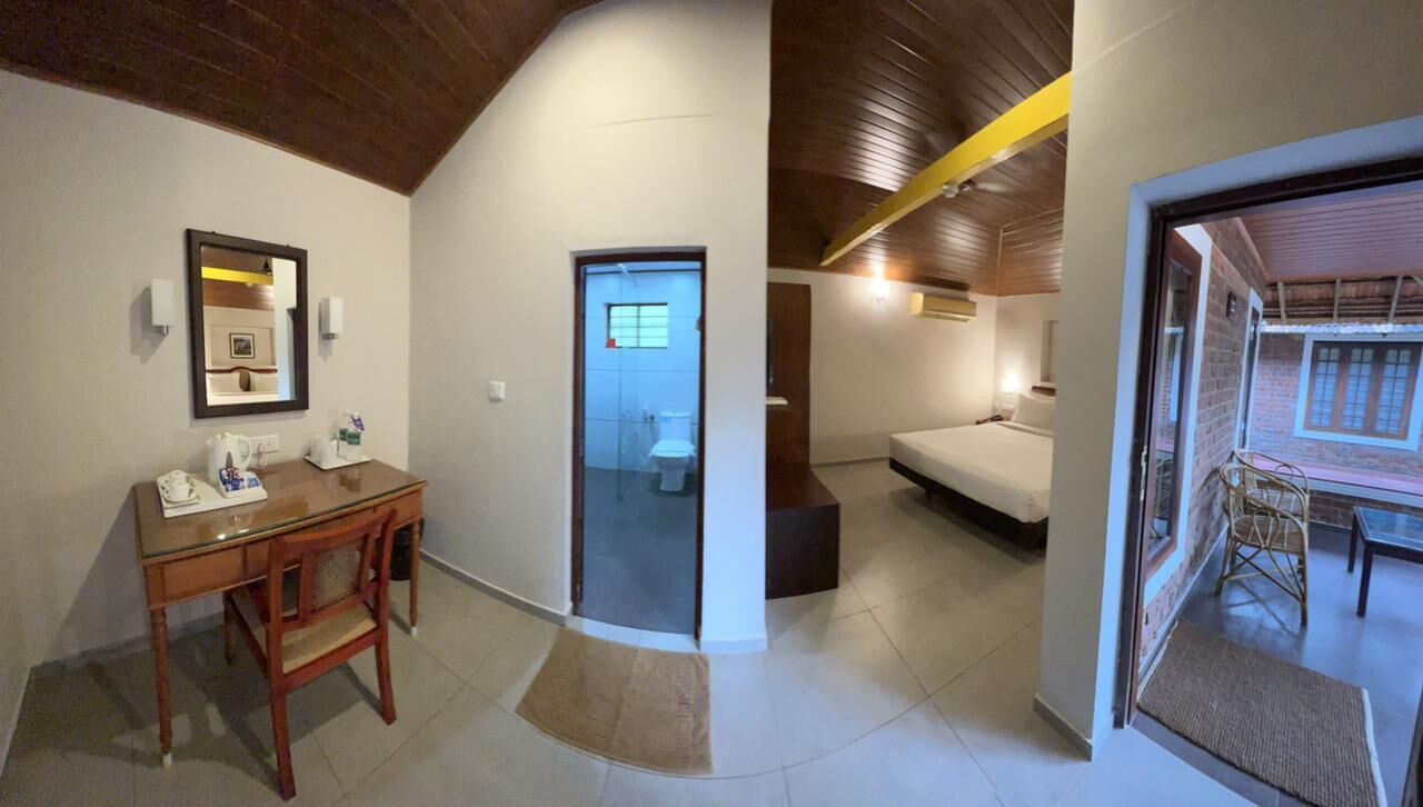 Una habitación con techo de madera, una cama, un escritorio con silla y una ventana pequeña.