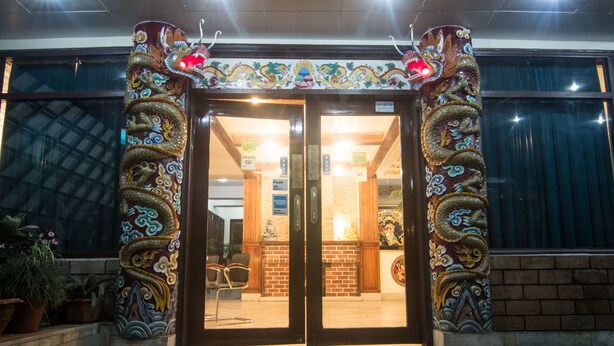 Entrada de un edificio con un diseño de dragón tradicional en los pilares y una puerta doble.