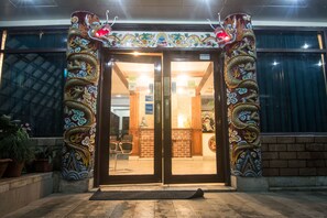 Une entrée d’immeuble ornée de motifs traditionnels de dragons sur les piliers et dotée d’une double porte.