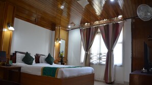 Un dormitorio con paneles de madera, una cama grande, mesitas de noche, un espejo y un ventilador de techo.