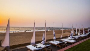 Ein Hotel direkt am Strand mit Reihen von Liegestühlen und Sonnenschirmen mit Blick auf den Ozean.