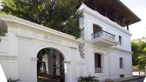 A white colonial-style building with a balcony and an arched entrance. - Le Dupleix (Puducherry)