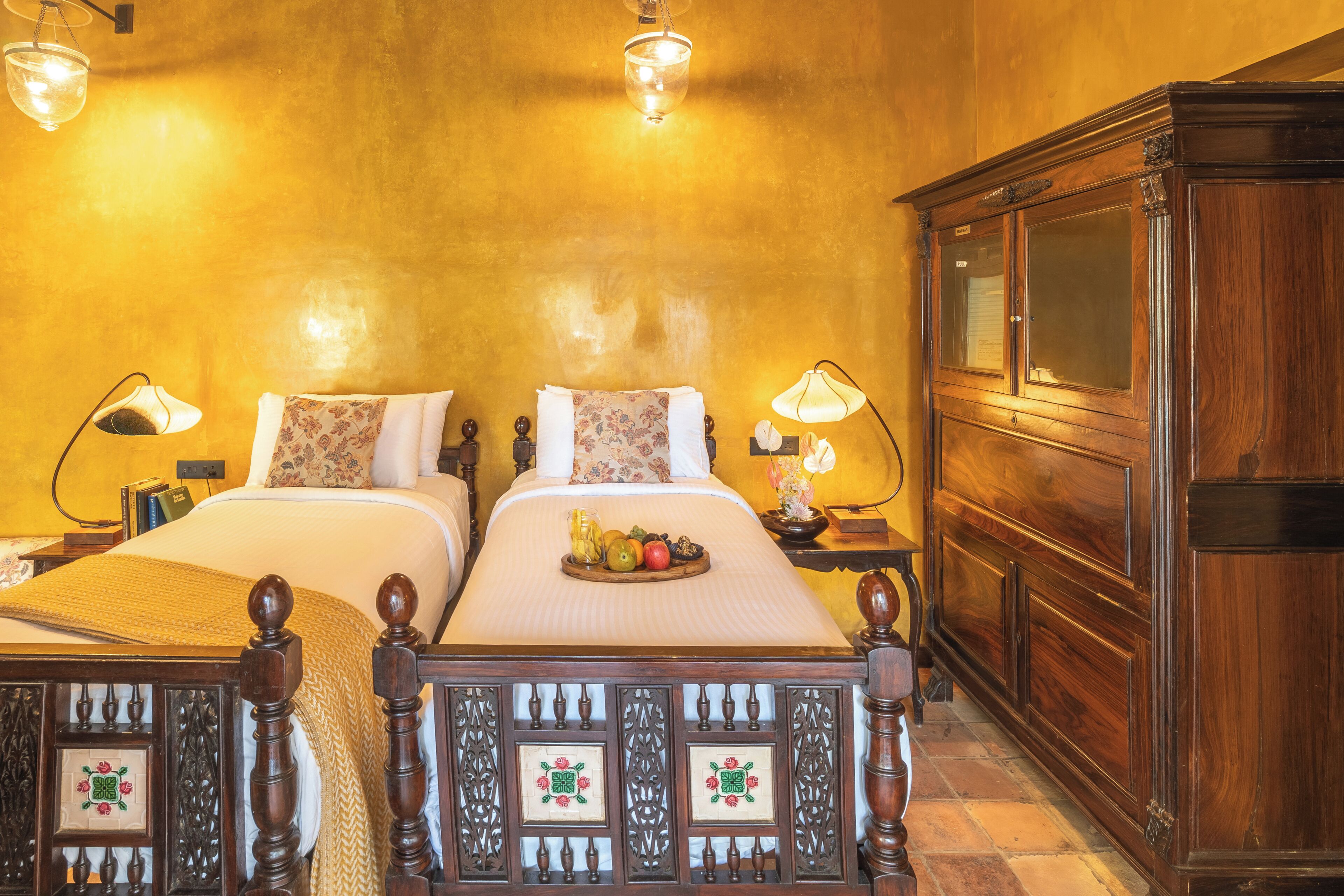 A double bed with a tray of fruit, two bedside lamps, and a wooden cabinet.