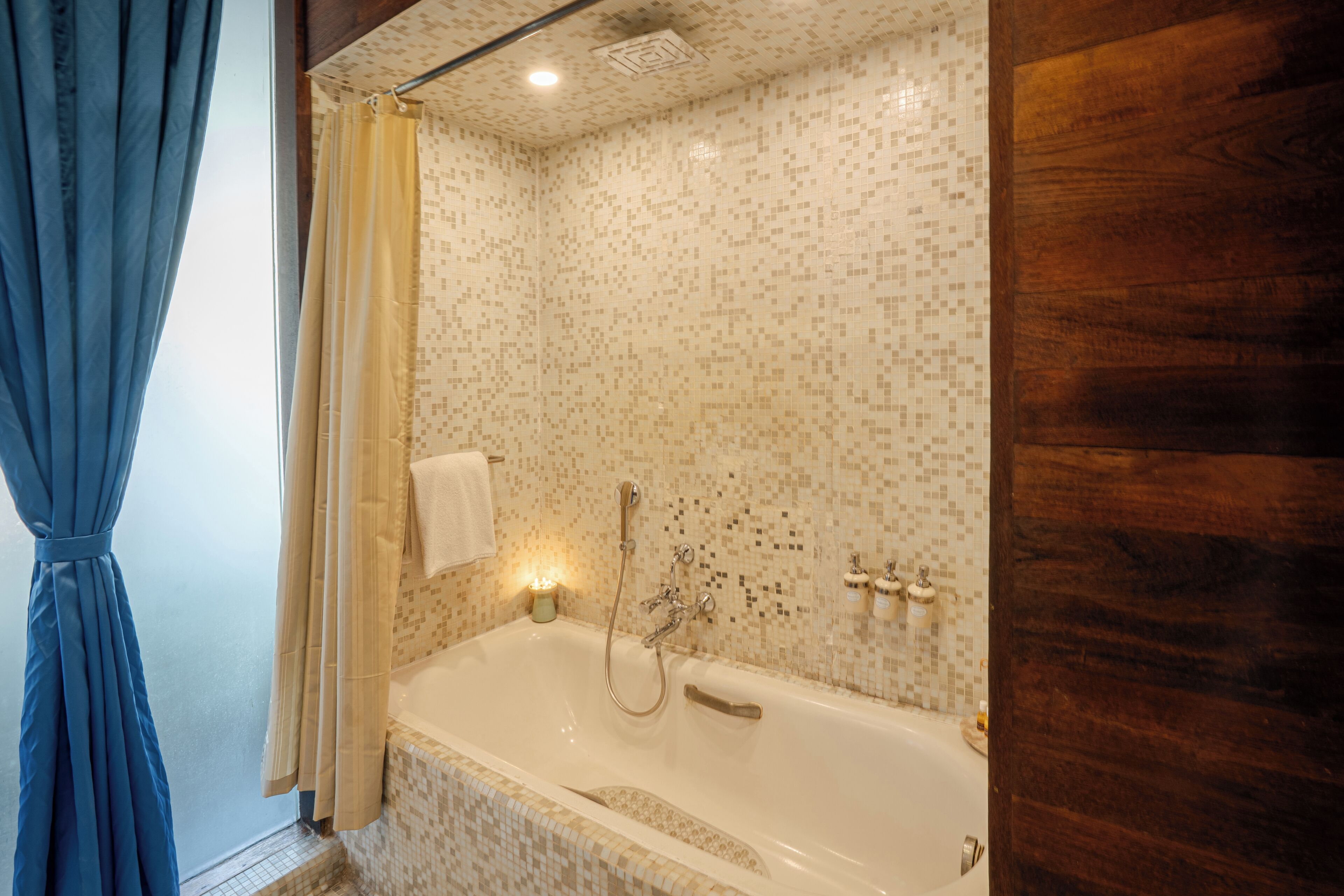 Een badkamer met een badkuip, douche en betegelde wanden.