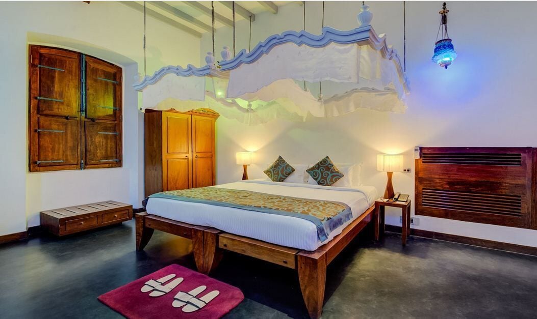 A bedroom with a wooden bed, two bedside tables, a wardrobe, and a hanging light fixture.