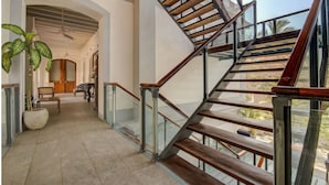 A modern staircase with glass railings and wooden steps, leading to an upper level. - Le Dupleix (Puducherry)