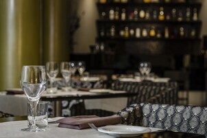A dining table set with a wine glass, a water glass, a folded napkin, a fork, and a plate.