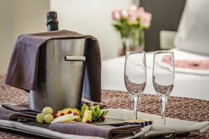 A breakfast setting with a coffee maker, two glasses of champagne, and a variety of fruits on a table.