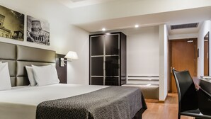 A hotel room with a large bed, a wardrobe, a desk, and a chair. - Eurostars Roma Aeterna (Rome)