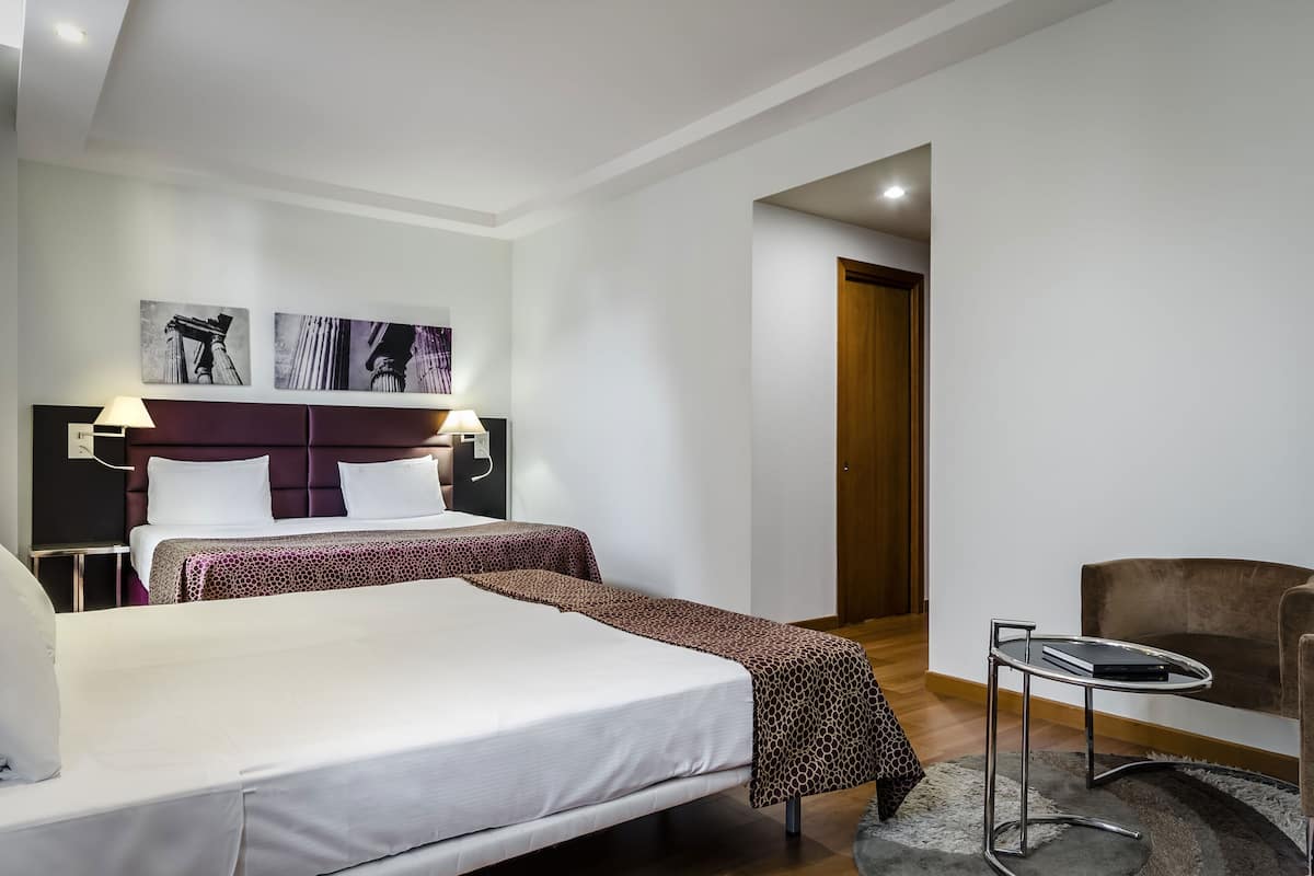 A hotel room with a large bed, two bedside tables, a chair, and artwork on the wall.