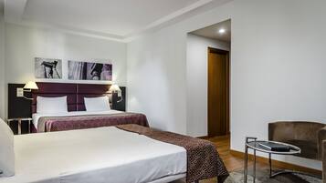 A hotel room with a large bed, two bedside tables, a chair, and artwork on the wall.