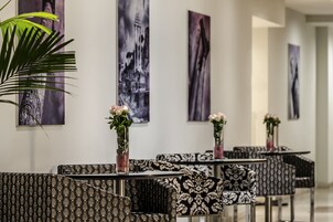 Un moderno vestíbulo de hotel con sofás estampados, jarrones blanco y negro con flores y obras de arte blanco y negro en las paredes.