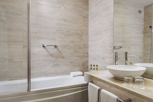 Une salle de bain moderne avec une douche à parois de verre, une baignoire blanche et un meuble-lavabo doté d’un grand évier et de deux petits verres.