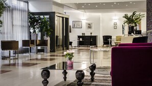 A modern hotel lobby with a glass coffee table, plush seating, and a large mirror. - Eurostars Roma Aeterna (Rome)