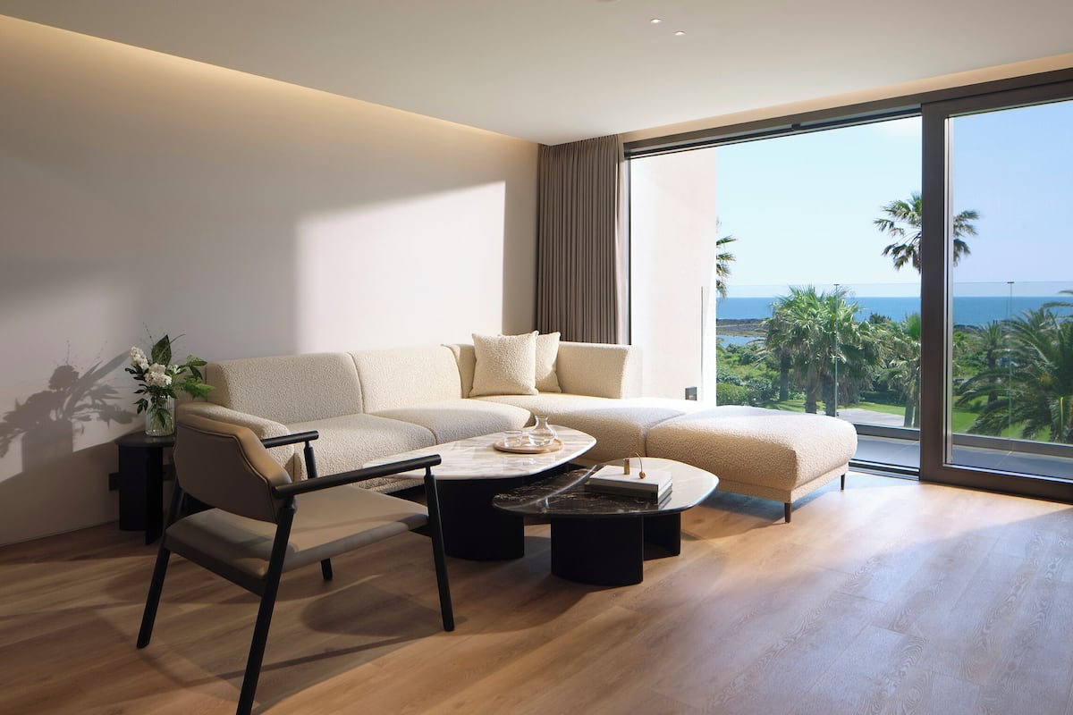Un salon moderne avec un canapé d’angle, une table basse et une vue sur l’océan.