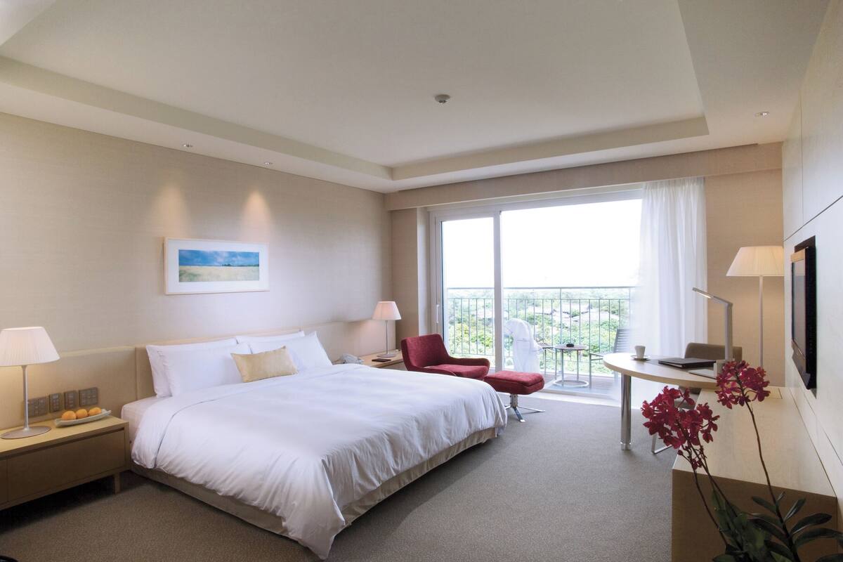 Une chambre d’hôtel avec un grand lit, un bureau, une chaise et un balcon avec vue.