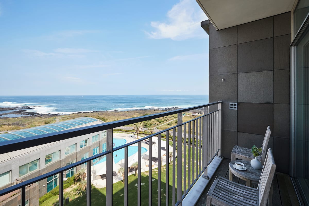 Un balcon avec vue sur une piscine et l’océan.