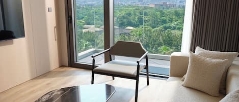 A modern living room with a large window, a sofa, a chair, and a black coffee table.